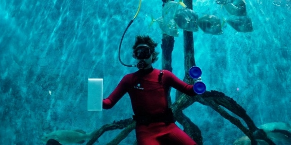 A couple splashing water on each other in emerald color waters.