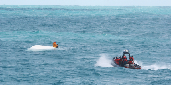 A couple splashing water on each other in emerald color waters.