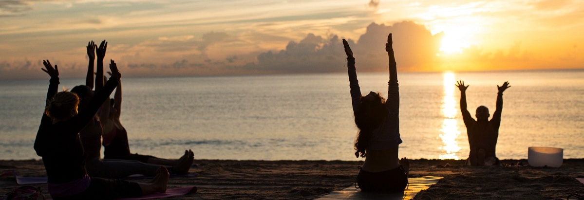 Several people on the shore doing yoga