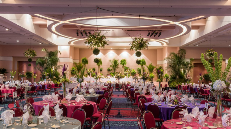 Ballroom set with round tables, pink tablecloths and tall flower arrangements